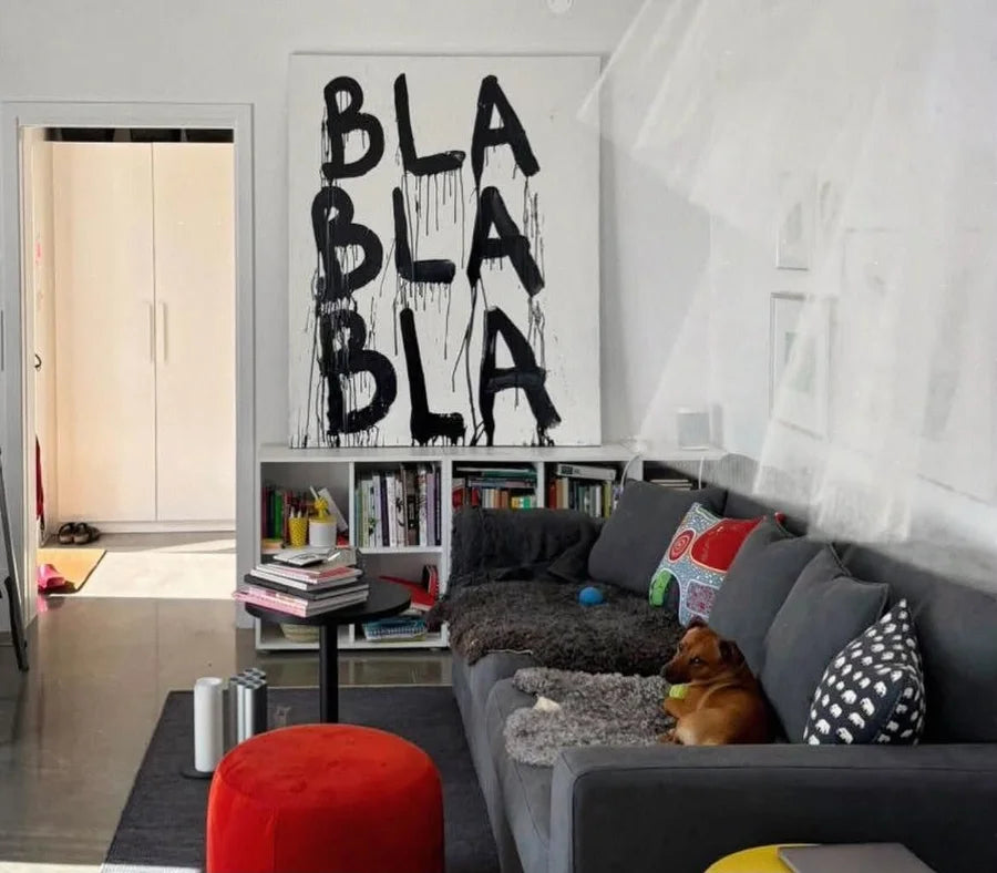 Large white canvas with dripping black BLA lettering above a bookshelf