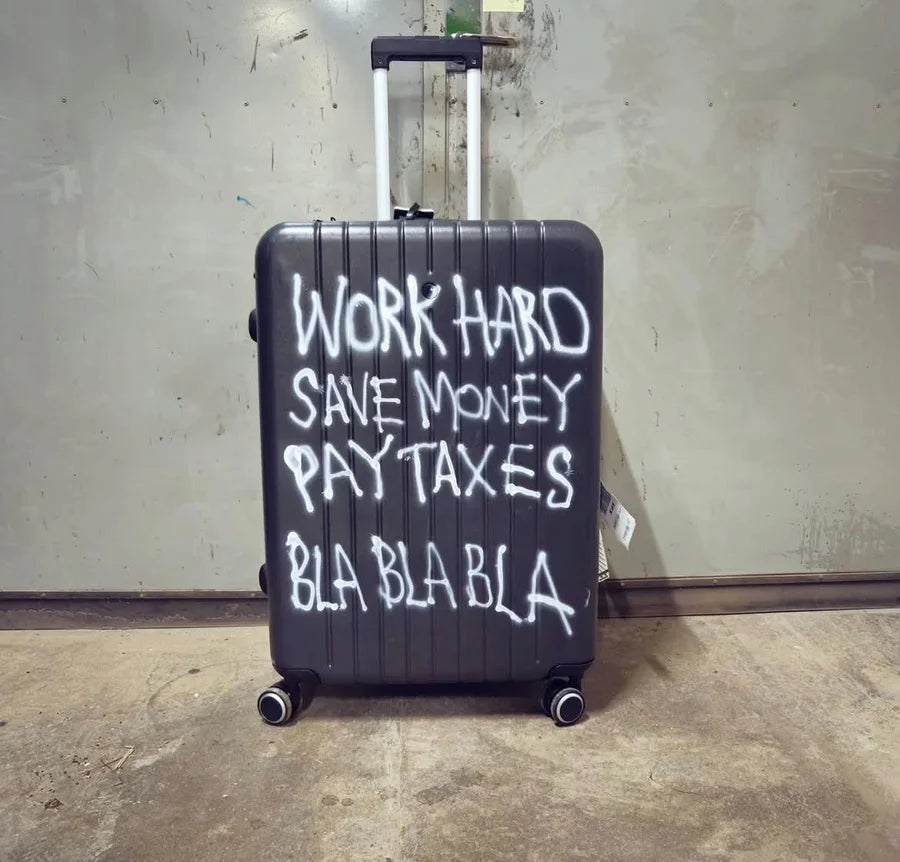 Black suitcase painted with white handwritten words and BLA BLA BLA